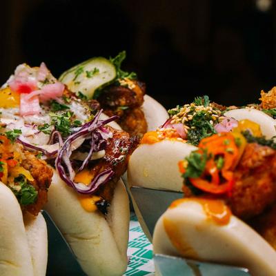 Stuffed bao buns topped with vegetables and herbs.