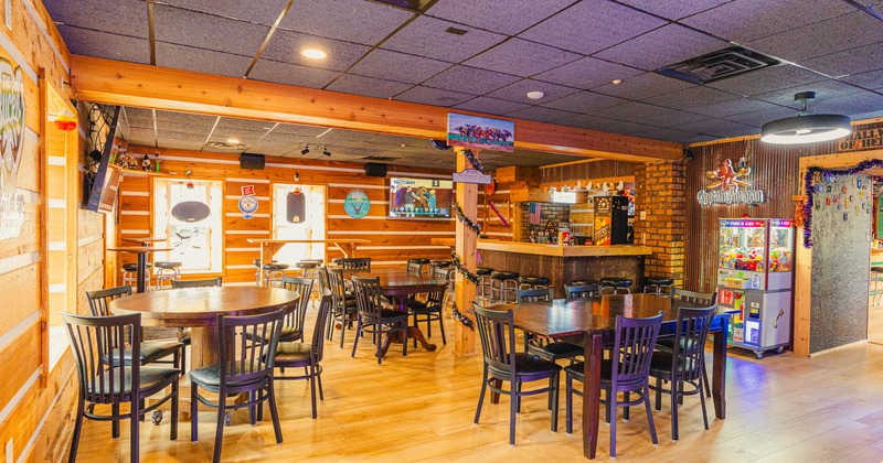 Interior, seating area, wooden top tables with wooden chairs, bar in the back, hardwood flooring