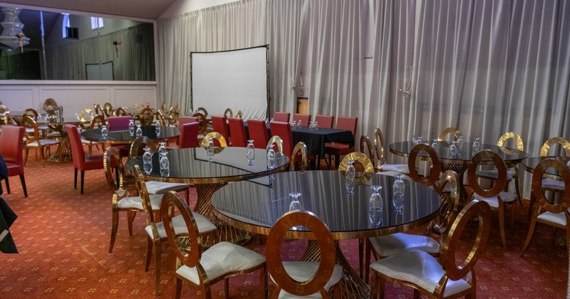 Interior, seating area, round tables for six people, projector screen, carpet flooring