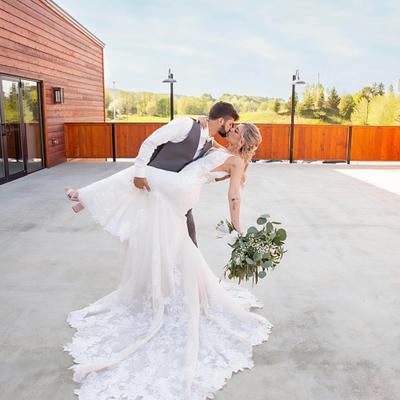 A groom kissing a bride in the outdoor setting.