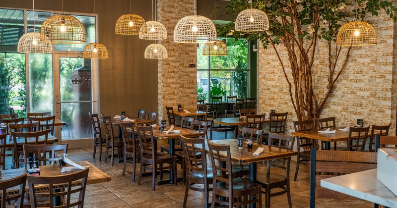 Dining area with wooden tables and chairs, pendant lights hanging from the ceiling