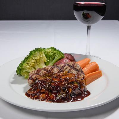 Steak with onion gravy, vegetables, and a glass of red wine.
