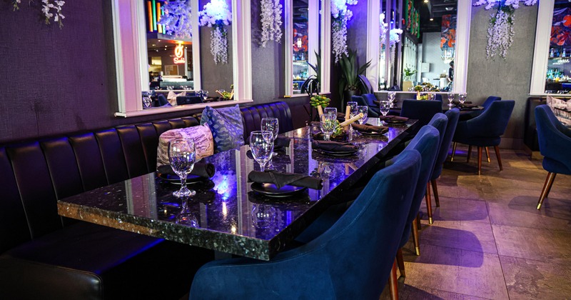 Modern and stylish restaurant interior dining area with a long marble dining table set for guests