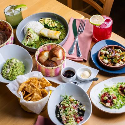 Colorful table spread with Mexican dishes and cocktails.