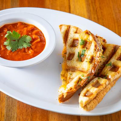 Grilled cheese sandwich served with tomato soup.