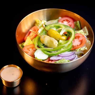 Salad with green peppers, tomato, lettuce, cucumber, red onion, and dressing.