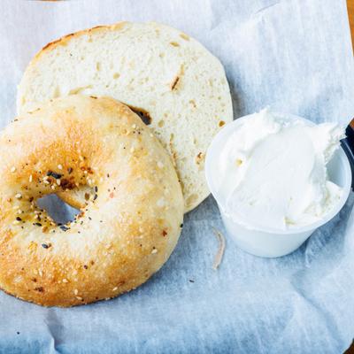 Bagel, sliced and served with a container of cream cheese.