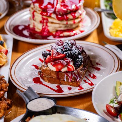 French toast topped with berries and sauce, surrounded by various other dishes.