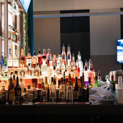Backlit bar shelf with numerous liquor bottles.