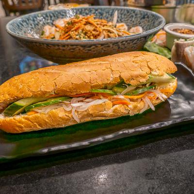 Crisp Vietnamese baguette sandwich on a plate filled with meat and fresh pickles.