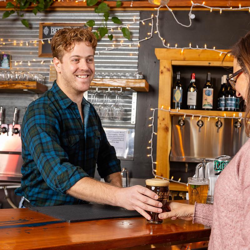Bartender serving a glass of beer on the bar counter.