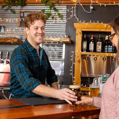 Bartender serving a glass of beer on the bar counter.