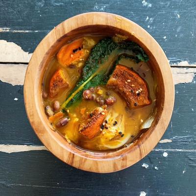 Bowl of vegetable soup with squash, kale and beans.