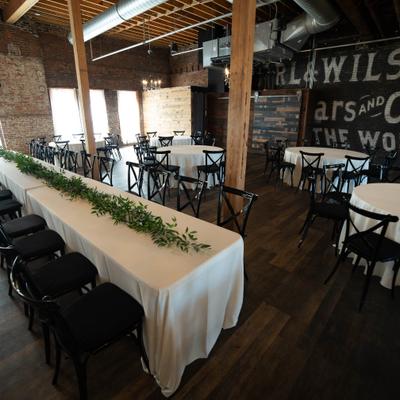Industrial event venue featuring long rectangular and round draped tables.