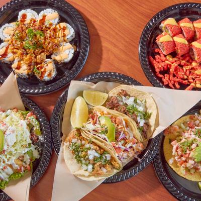 Assorted dishes including tacos and sushi rolls on a table.