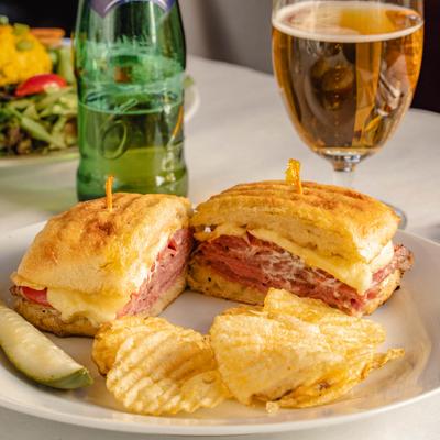 Grilled roast beef and cheese sandwich, with potato chips.