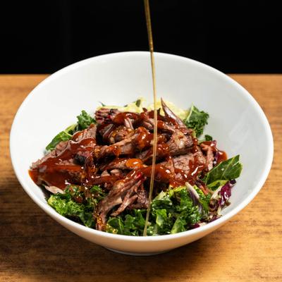 Brisket Salad seing drizzled with barbecue sauce.