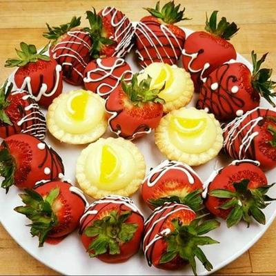 Chocolate-covered strawberries with drizzle and lemon tarts on a white plate.