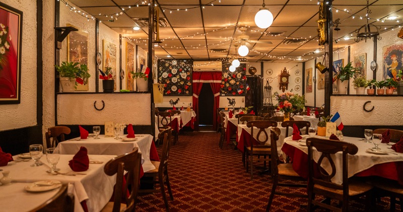 Interior seating area with tables set for dining, vintage posters on the walls