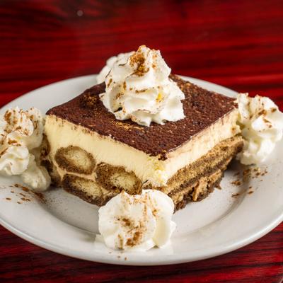 Tiramisu dusted with cocoa powder and served with whipped cream.