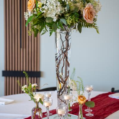 Tall floral centerpiece with candles on an event table.