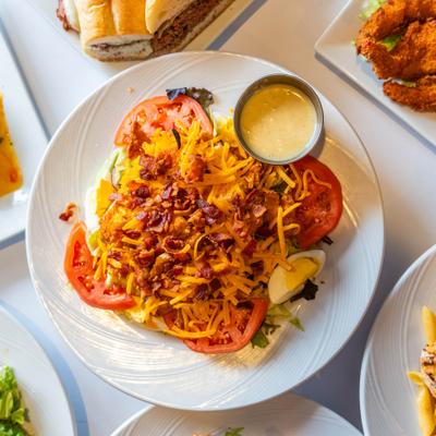 Crispy chicken salad with bacon, tomato, egg, shredded cheddar, and a cup of dressing