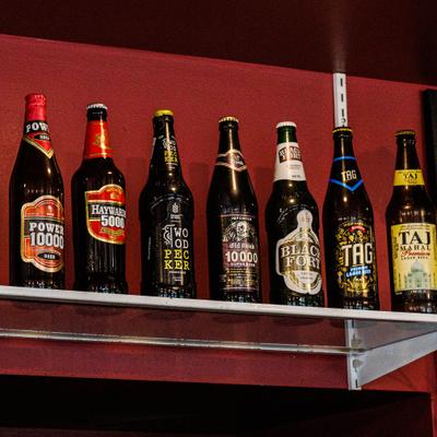 Assorted beer bottles lined up on a bar shelf.