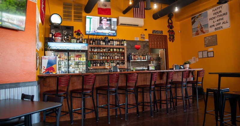 Interior, bar area, wooden top bar with bar stools, refrigerator and drink shelves in the back