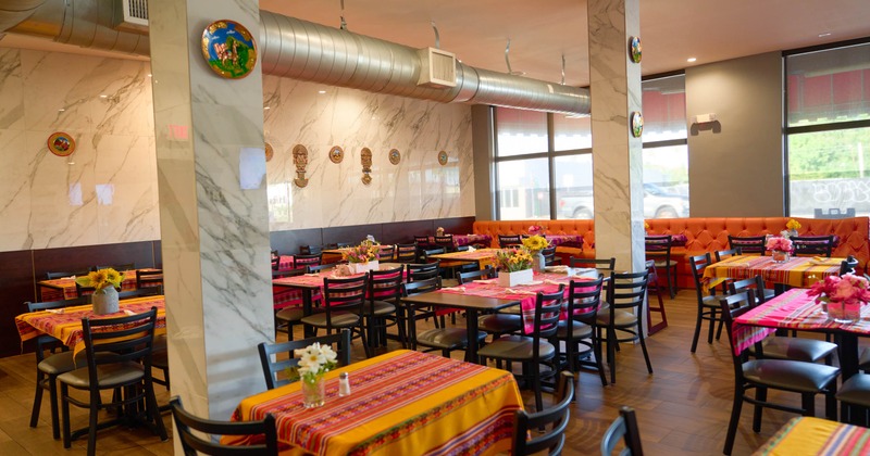 Interior with orange booth seating, and colorful table runners over wooden tables
