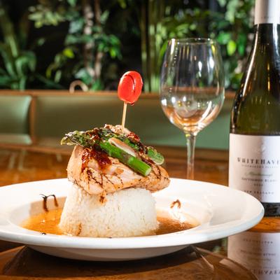 Grilled salmon dish on a table with wine.