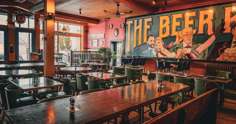 Interior, dining area, long wooden table in front, regular tables, entrance in the back