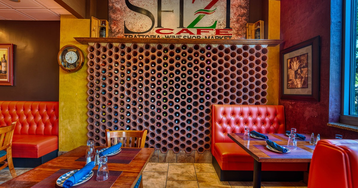Interior with red booths, wooden tables and a wall of circular wine racks.
