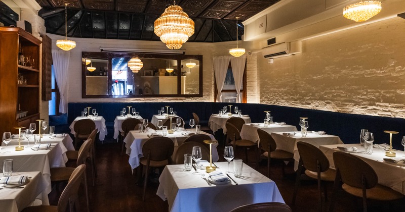 Elegant dimly lit restaurant interior with white tablecloths and chandeliers