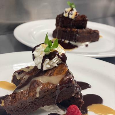 Chocolate brownies topped with whipped cream, chocolate sauce, and a mint leaf.