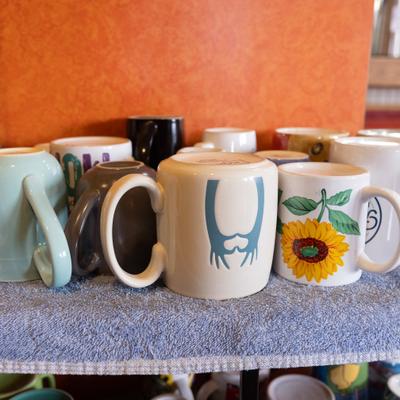 Assorted ceramic mugs displayed on a shelf.