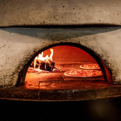 Two pizzas being baked in a wood fired oven.