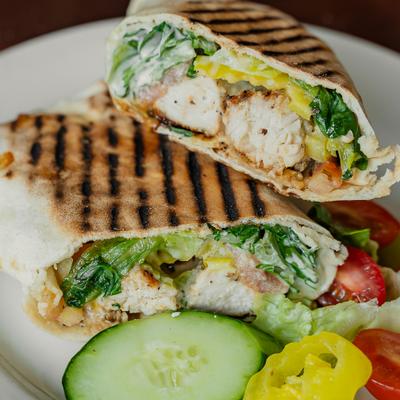 Grilled Chicken Wrap sliced in half and served with a side salad.