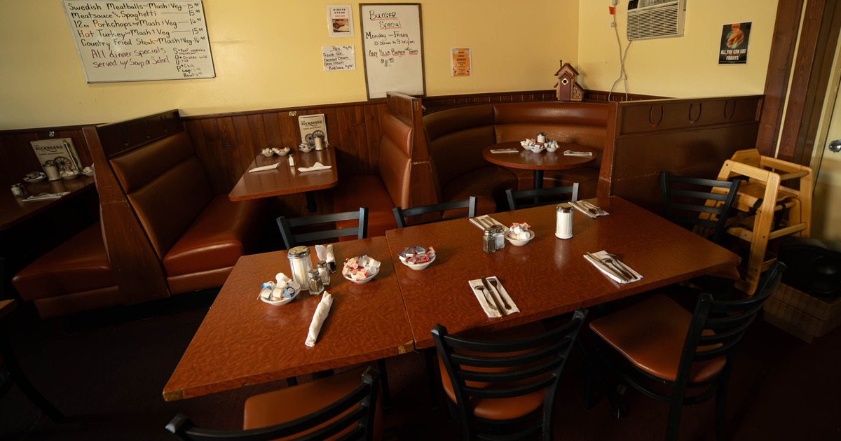 Dining area with a large wooden table and several booths in a restaurant setting