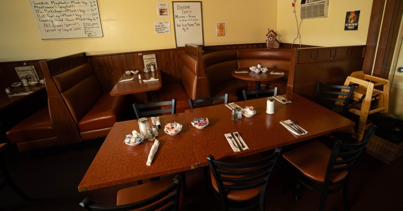Dining area with a large wooden table and several booths in a restaurant setting