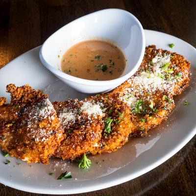 Fried mozzarella bites topped with grated Parmesan, served with a cup of creamy sauce.
