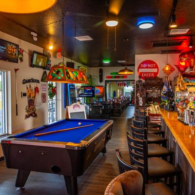 Interior with pool table, stocked bar counter and various decorations.