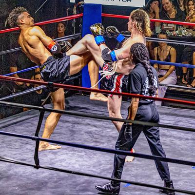 Two fighters engaged in a kickboxing match before an audience.