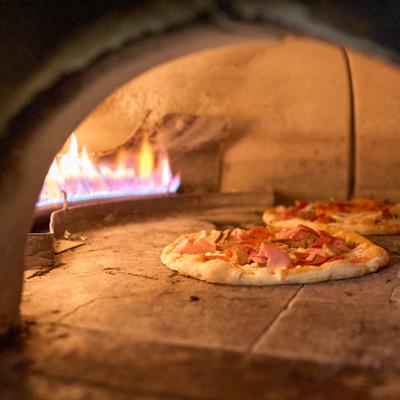 Pizzas baking on stone in a wood fired oven.