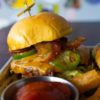 Bacon cheeseburger with cheddar, jalapenos, lettuce, and a side of fries.