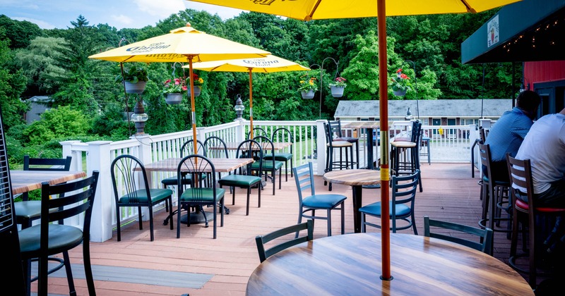 Outdoor patio, umbrellas, wooden tables, and black chairs