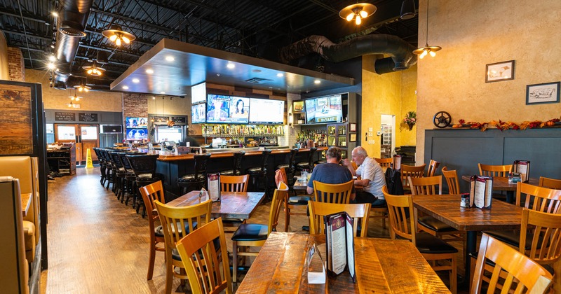 Interior, tables, chairs, customers sitting, LED screens, lighting, counter, stacked drinks, decorations