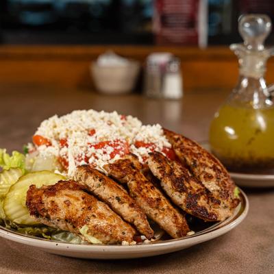 Mixed salad with grilled chicken strips, crumbled cheese, and pickles.