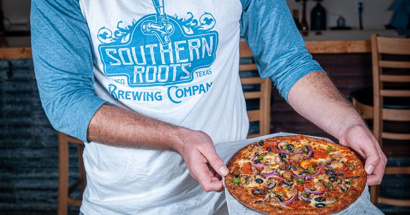 Staff member holding pizza