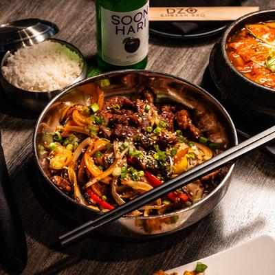 Korean beef stir-fry served with white rice, spicy stew, and plum soju.