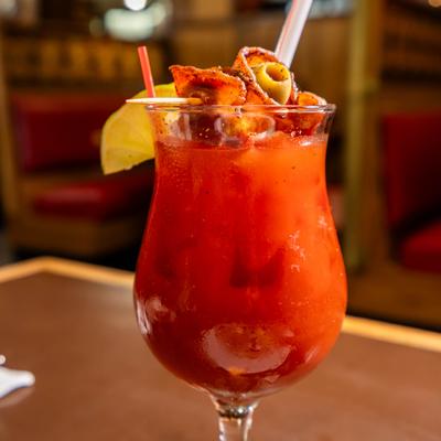 Bloody Mary cocktail served in a curved glass with various garnishes and a straw.